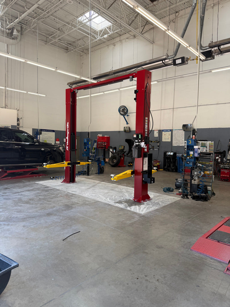 Red Challenger two-post vehicle lift installed by Alamo Equipment in a commercial service bay